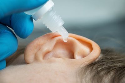 Hearing health care professional reliving ear pain from a patient with ear drops at a Connect Hearing center in TX, FL, or CA.