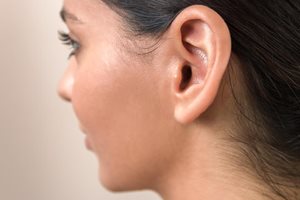 A side view of a young woman's head showcasing her ear.